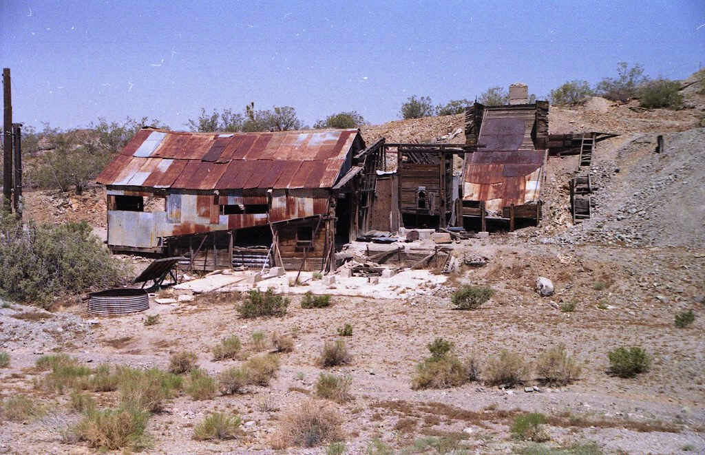 Decrepit tin buildings on a hillside in the desert.